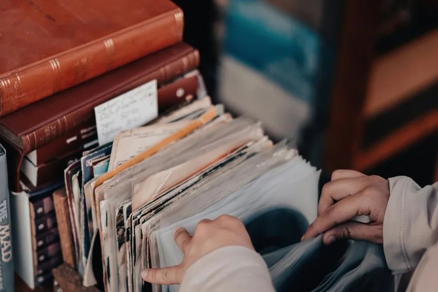 Hands flipping through a well-kept stack of records under warm light.